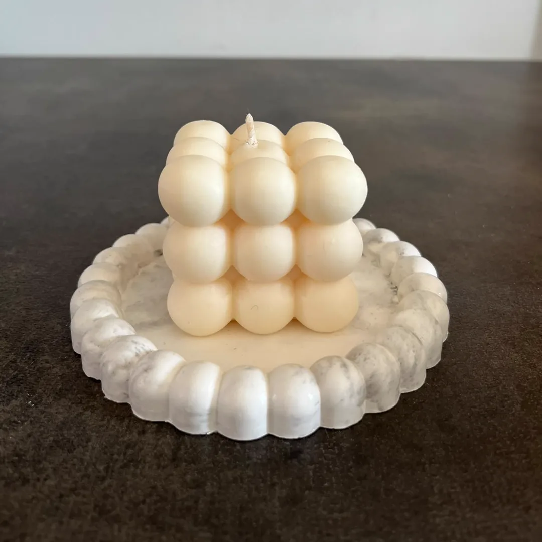 Vela de soja en forma de cubo de burbujas color marfil sobre bandeja de yeso